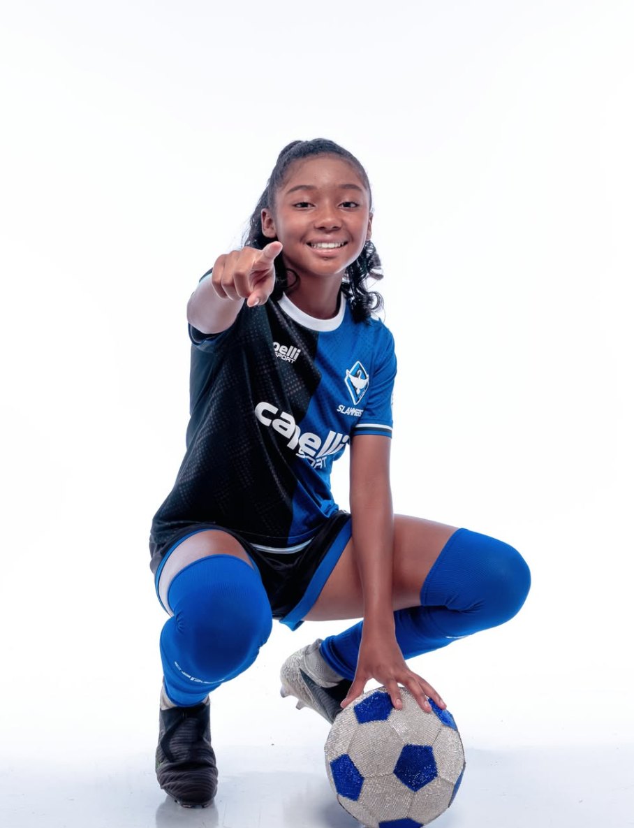 London crouched over a ball, pointing at the camera